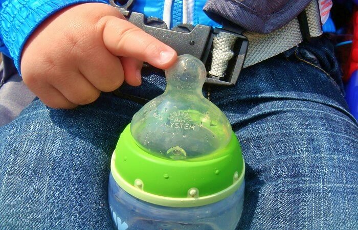 closeup on baby finger touching baby bottle 