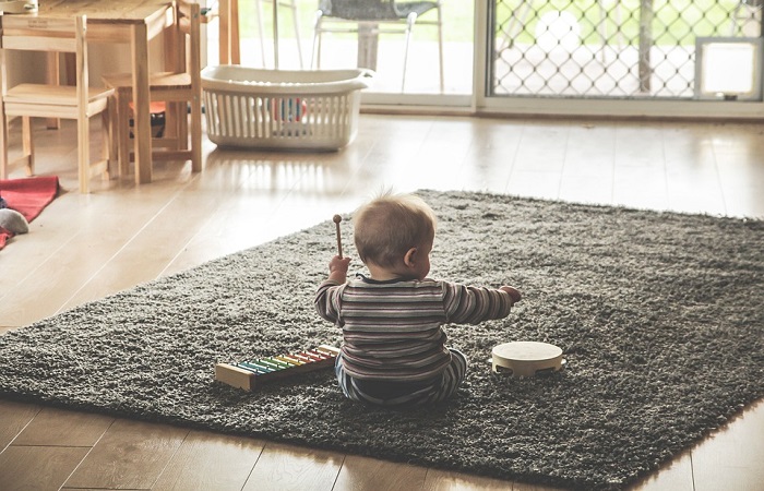 toddler playing on a rug seen from behind 