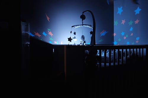 crib in a dark room with starry night light