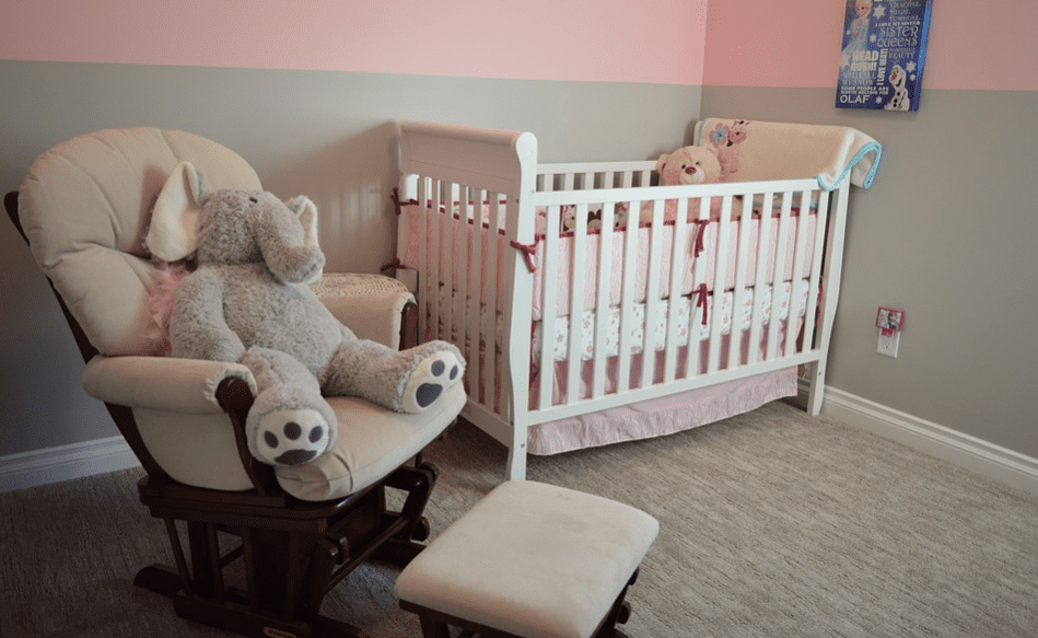 chair with stuffed toy beside white crib