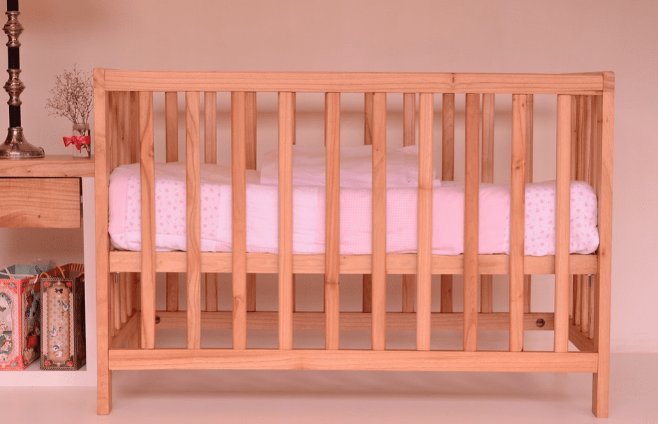 brown wooden nursery crib with pink fitted sheet