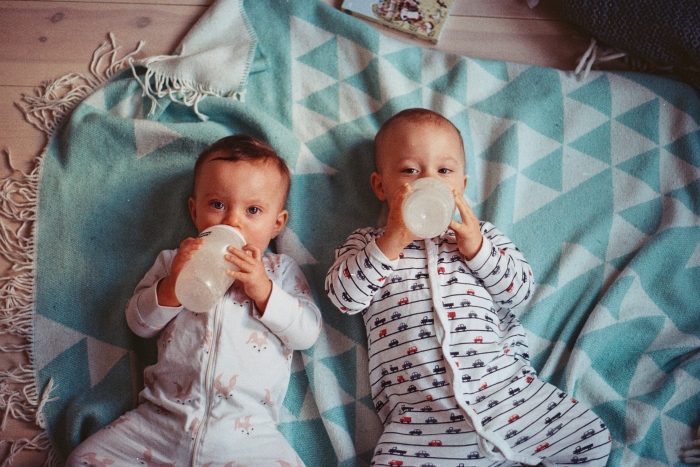 two babies drinking from baby bottles