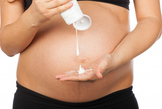 Pregnant woman using lotion to prevent stretch marks